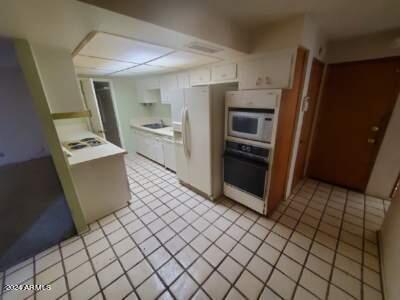 kitchen with white cabinets, white appliances, and light tile patterned flooring