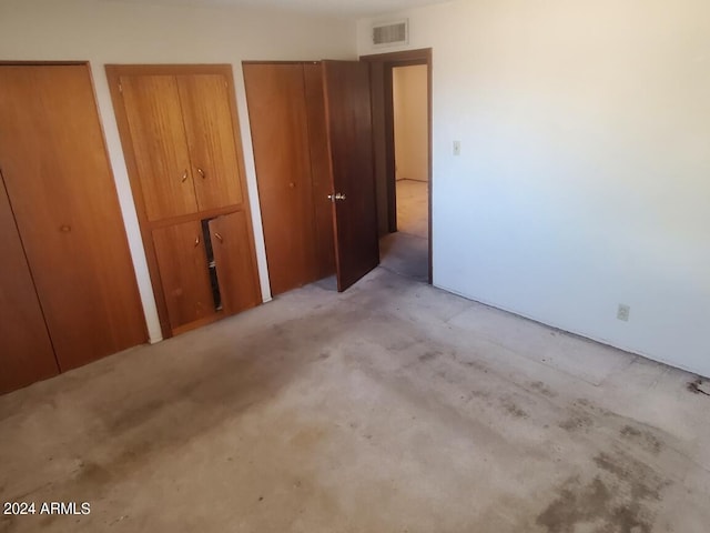 unfurnished bedroom with two closets and visible vents