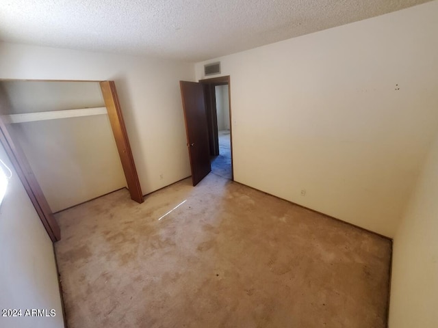 unfurnished bedroom with a textured ceiling, visible vents, and light carpet