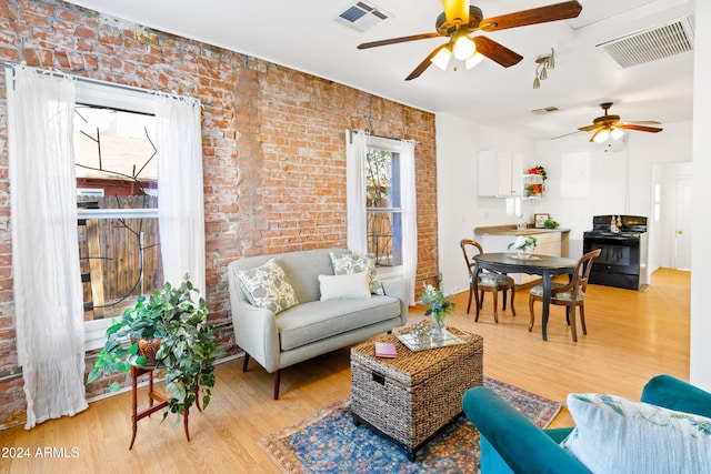 living room with ceiling fan, brick wall, and light hardwood / wood-style flooring