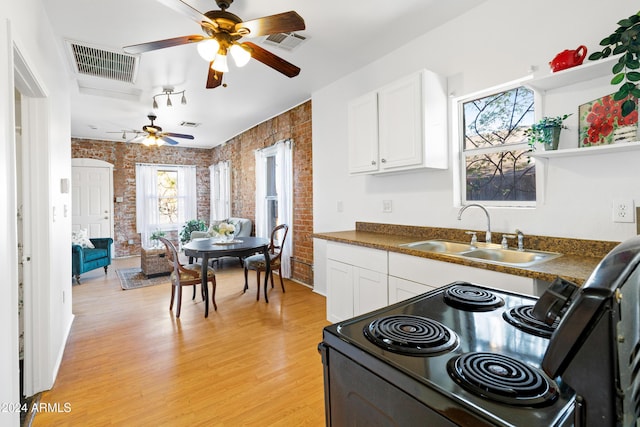 kitchen featuring sink, electric range, light wood-type flooring, white cabinetry, and brick wall