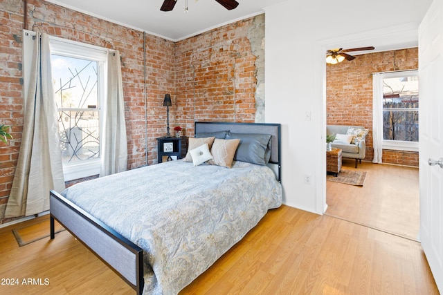 bedroom featuring ornamental molding, brick wall, ceiling fan, hardwood / wood-style floors, and a wood stove