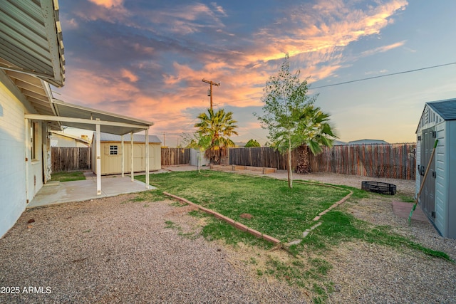 117 Peretz Cir, Morristown, AZ 85342 - yard at dusk featuring an outdoor structure, a fenced backyard, a patio, and a storage shed