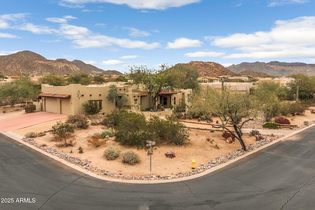 adobe home with a garage, driveway, a mountain view, and stucco siding