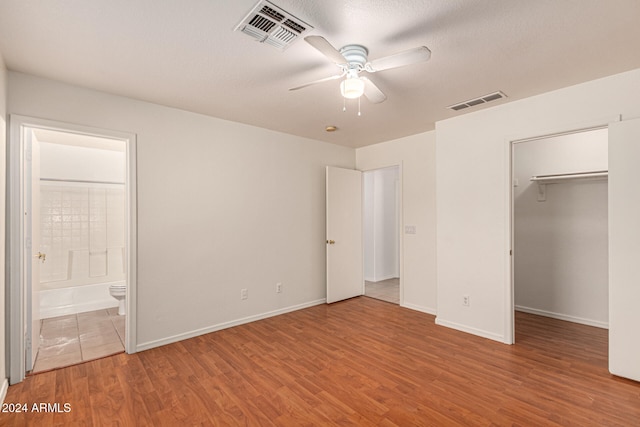 unfurnished bedroom with ceiling fan, a textured ceiling, connected bathroom, light hardwood / wood-style floors, and a closet