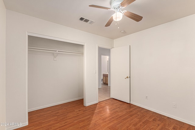 unfurnished bedroom with ceiling fan, light wood-type flooring, and a closet