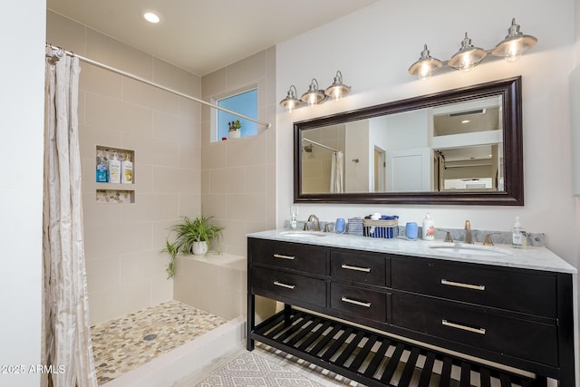 bathroom with a sink, a shower stall, and double vanity