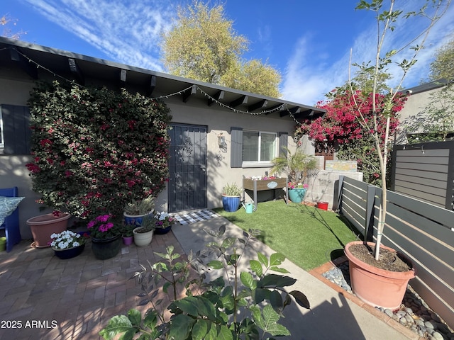 rear view of house featuring a lawn, a patio, fence, and stucco siding