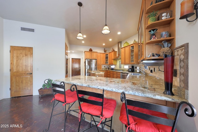 kitchen with wall chimney exhaust hood, sink, decorative light fixtures, appliances with stainless steel finishes, and kitchen peninsula