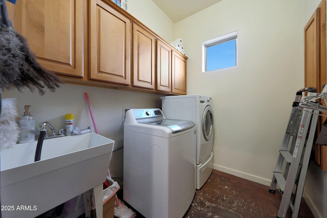 clothes washing area with separate washer and dryer, sink, and cabinets