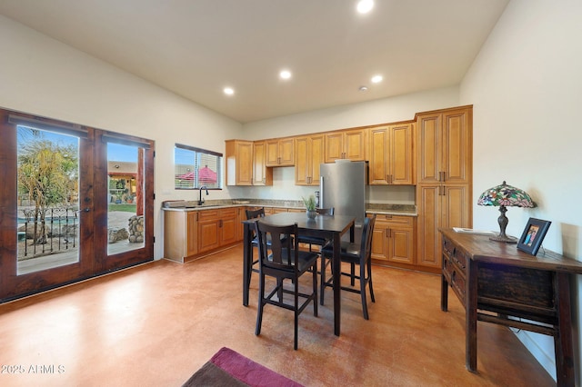 kitchen with a kitchen island, stainless steel refrigerator, sink, a kitchen bar, and french doors