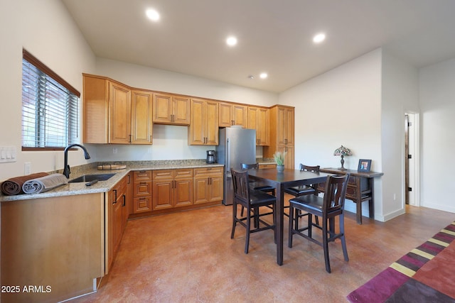 kitchen with stainless steel fridge, light stone countertops, and sink