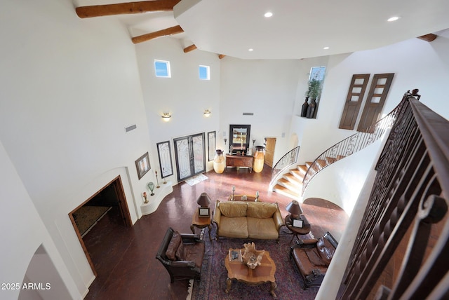 living room featuring a high ceiling, wood-type flooring, and beam ceiling