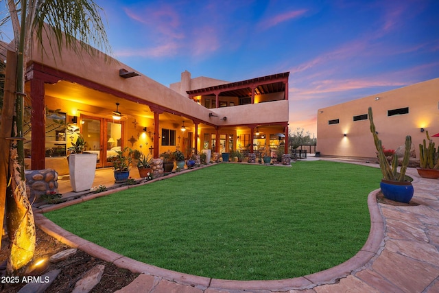 yard at dusk featuring ceiling fan