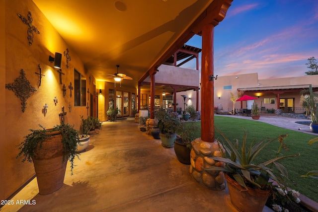 patio terrace at dusk with ceiling fan and a lawn