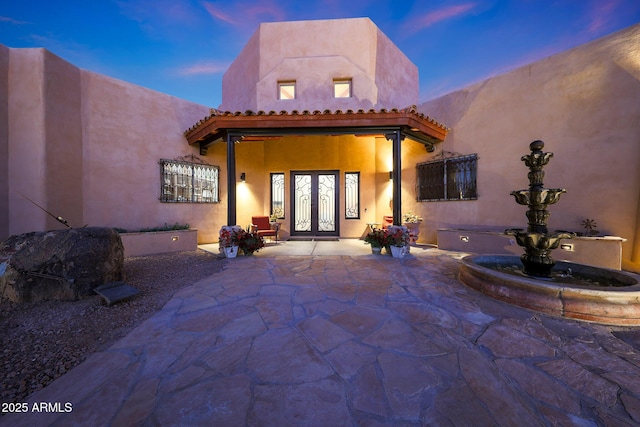 back house at dusk featuring a patio and french doors