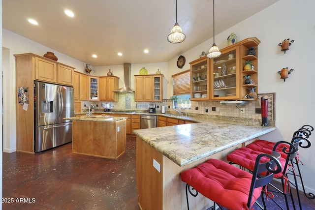 kitchen featuring wall chimney exhaust hood, decorative light fixtures, a center island, appliances with stainless steel finishes, and kitchen peninsula