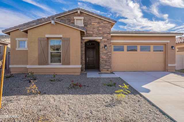 view of front of home with stucco siding, driveway, stone siding, a tiled roof, and an attached garage