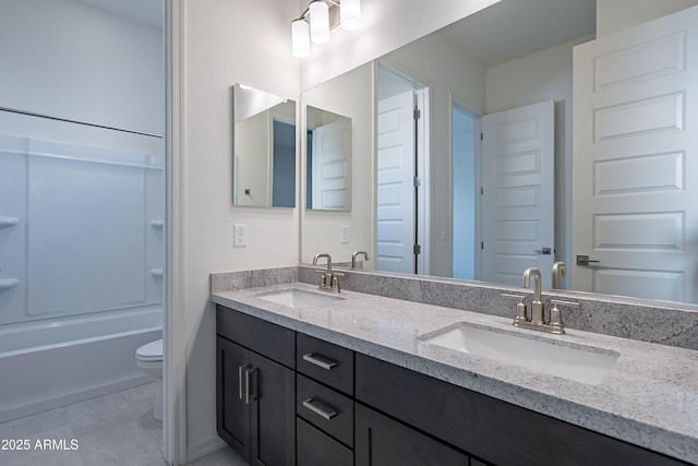 full bath featuring toilet, double vanity, a sink, and shower / bath combination