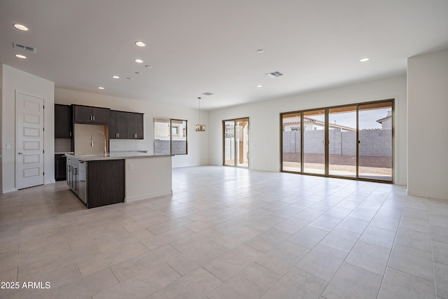 kitchen with visible vents, open floor plan, a center island with sink, and plenty of natural light