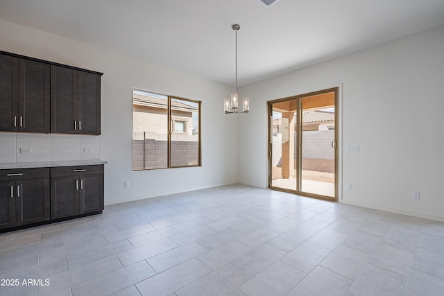 unfurnished dining area with light tile patterned floors, a chandelier, and baseboards