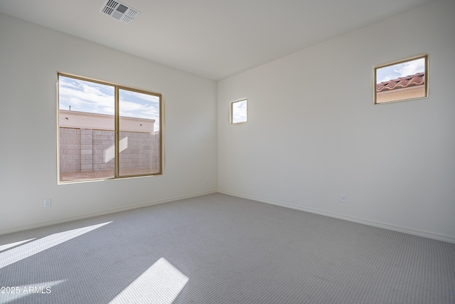carpeted spare room featuring baseboards and visible vents