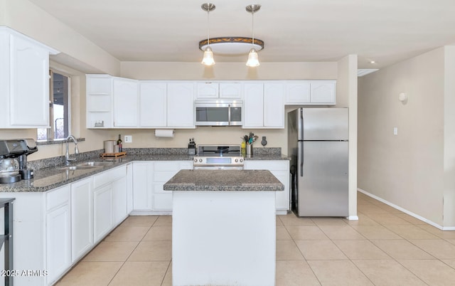 kitchen featuring white cabinetry, sink, stainless steel appliances, pendant lighting, and a kitchen island