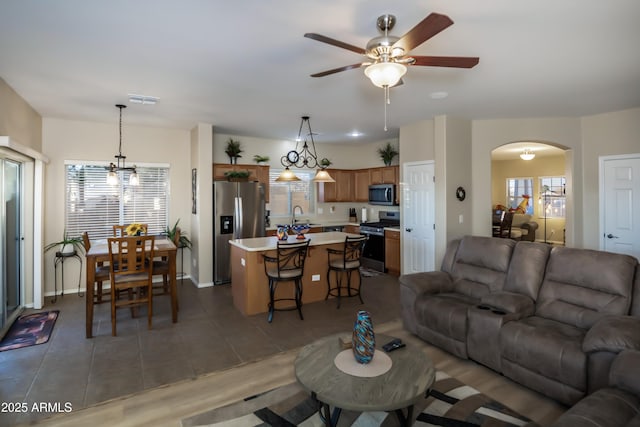 living room featuring ceiling fan with notable chandelier and sink