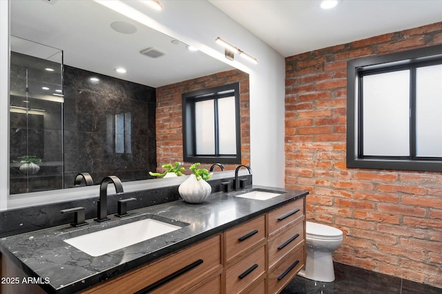 bathroom featuring vanity, a healthy amount of sunlight, toilet, and brick wall