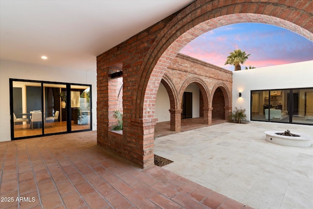 patio terrace at dusk featuring an outdoor fire pit