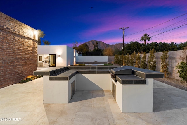 patio terrace at dusk featuring exterior kitchen