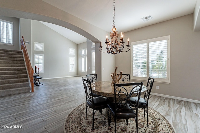 dining area featuring hardwood / wood-style floors, a notable chandelier, and vaulted ceiling