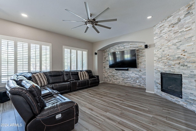 living room with a stone fireplace, hardwood / wood-style flooring, and ceiling fan