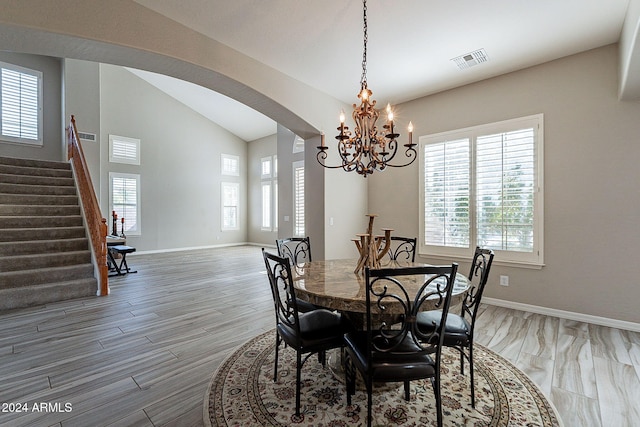 1912 E Gemini Pl, Chandler, AZ 85249 - dining room featuring arched walkways, lofted ceiling, light wood-type flooring, a chandelier, and stairway
