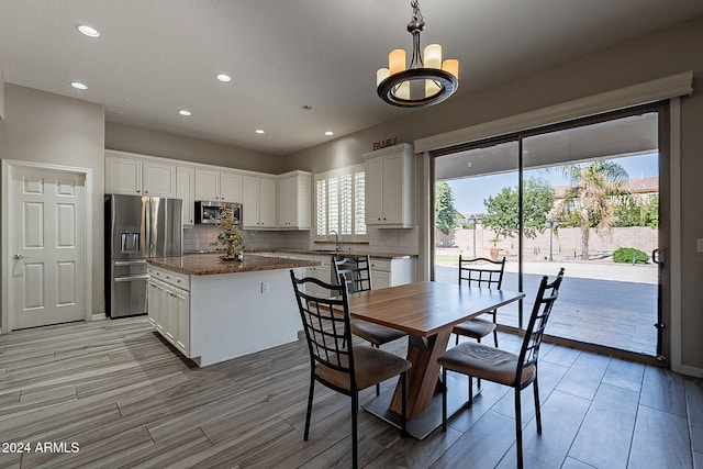 dining space with a wealth of natural light, sink, a notable chandelier, and light hardwood / wood-style flooring