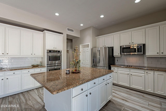 kitchen with a kitchen island, white cabinets, and stainless steel appliances