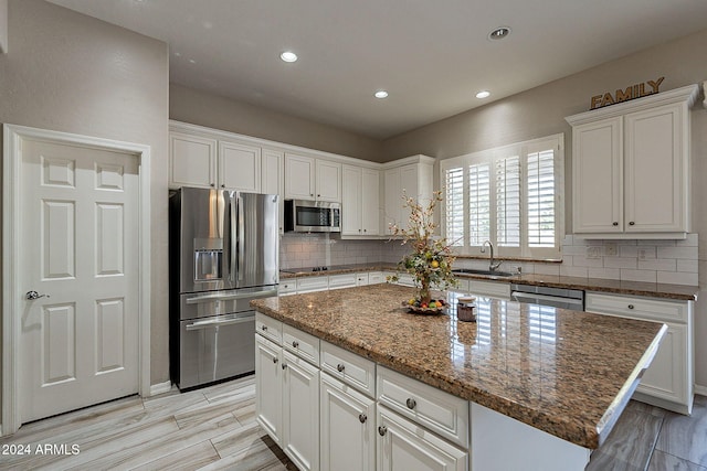 kitchen featuring dark stone counters, a center island, white cabinets, and stainless steel appliances