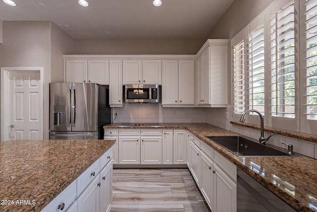 kitchen with white cabinets, stainless steel appliances, sink, and dark stone countertops