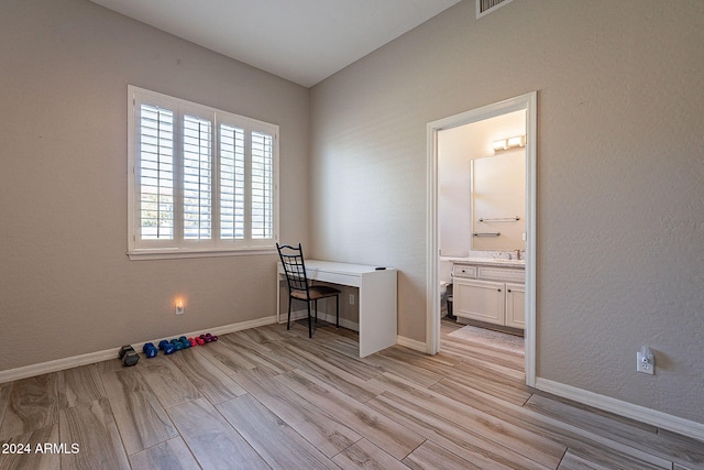 office with light wood-type flooring and sink