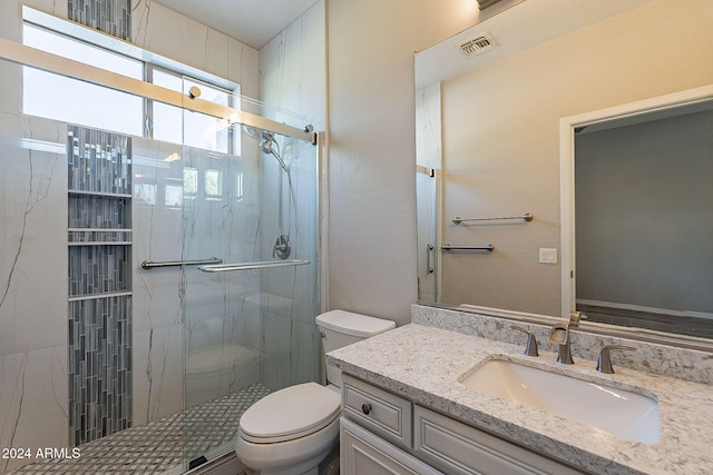 bathroom featuring a shower with door, vanity, and toilet