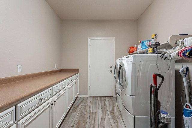 laundry area featuring cabinets, washer and dryer, and light hardwood / wood-style floors