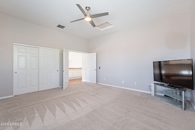 unfurnished bedroom with light colored carpet, ceiling fan, and a closet