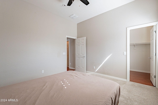 unfurnished bedroom with a closet, a spacious closet, carpet floors, lofted ceiling, and ceiling fan