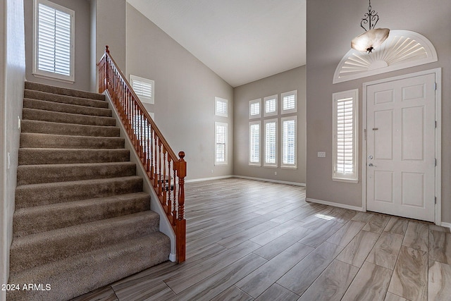 foyer entrance with light hardwood / wood-style floors and high vaulted ceiling