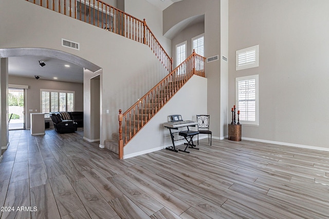 entrance foyer with light hardwood / wood-style floors and a towering ceiling