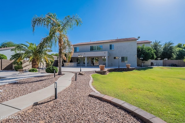 rear view of house featuring a patio area and a yard