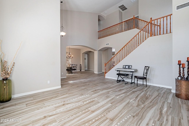 entrance foyer featuring high vaulted ceiling, a notable chandelier, and light wood-type flooring