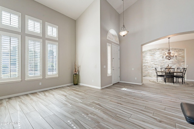 foyer with high vaulted ceiling, plenty of natural light, and light wood-type flooring