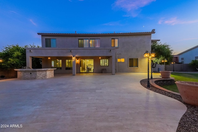 back house at dusk featuring a patio