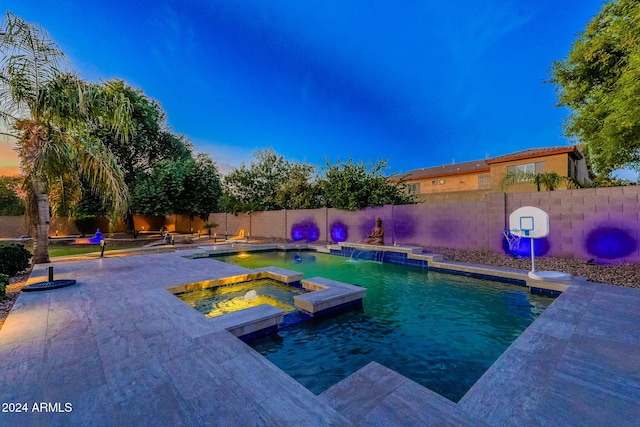 pool at dusk featuring an in ground hot tub and pool water feature